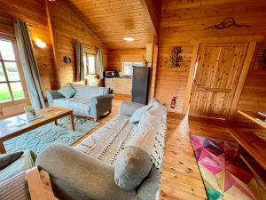 una sala de estar con sofá y sillas en una cabaña en Lake Pochard, Oak Lodge en South Cerney