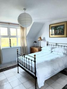 - une chambre avec un grand lit et des draps blancs dans l'établissement Stunning apartment set in private native woodland, à Ramelton