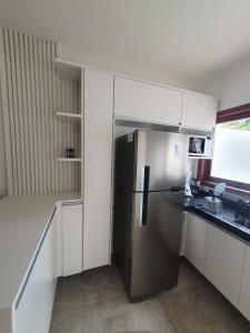 einen Kühlschrank aus Edelstahl in einer Küche mit weißen Schränken in der Unterkunft Casas a 5 min do Centro Histórico in Paraty