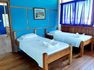 2 camas en una habitación con paredes y ventanas azules en Hurvínek, en Montañita