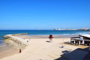 - une plage avec des personnes, un bâtiment et l'océan dans l'établissement Apartamento Cádiz Costa, à Cadix