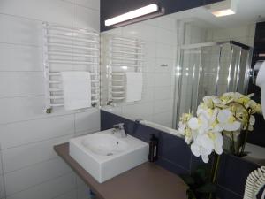a bathroom with a sink and a vase of flowers at AGAT Apartament Czarna Góra in Sienna +16 photos