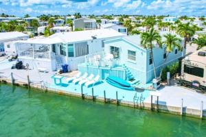 a large blue house with a boat in the water at NAUTILUS...ocean front cottage retreat ~ in Cudjoe Key