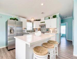 una cocina con una gran isla blanca con taburetes en NAUTILUS...ocean front cottage retreat ~, en Cudjoe Key