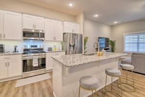 a kitchen with white cabinets and a counter with bar stools at Charming Ozark Abode with Yard and Pool Access in Ozark