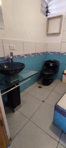 a bathroom with a black toilet and a sink at cusco pasay in Cusco