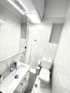 La salle de bains blanche est pourvue de toilettes et d'un lavabo. dans l'établissement Classic 2 Bedroom Apartment Next to Metro - Marousi, à Athènes