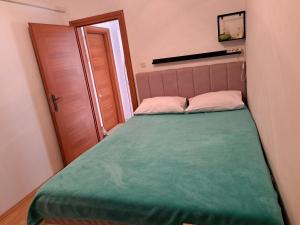 Un pequeño dormitorio con una cama verde y una puerta en Mateo, en Dugi Rat