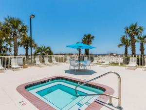 une piscine avec une table et un parasol dans l'établissement Regency Isle #605, à Orange Beach