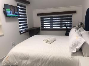 Una cama blanca con una toalla encima. en Liso’s Place Guest House en Pretoria