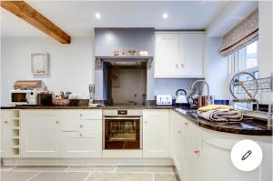 a kitchen with white cabinets and a sink at Rustic Retreats Jacks Cottage with Hot Tub & Alpaca Walking Experiences in Matlock
