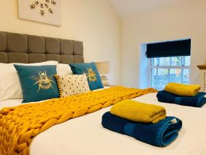 a large bed with yellow and blue pillows on it at Rustic Retreats Jacks Cottage with Hot Tub & Alpaca Walking Experiences in Matlock