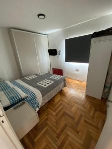 a small bedroom with a bed and a wooden floor at Departamento frente al mar con cochera! in Mar del Plata