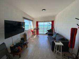 ein Wohnzimmer mit einem blauen Sofa und einem Flachbild-TV in der Unterkunft Departamento frente al mar con cochera! in Mar del Plata