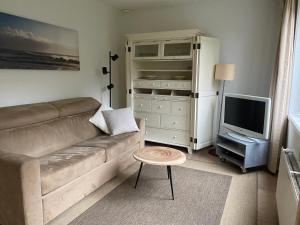a living room with a couch and a television at Apartment Ella with free privat parking in Zandvoort