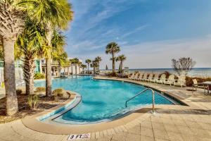a swimming pool with palm trees and chairs at AQUA RESORT! Beachfront, 3 Bedroom Condo! 2 Bedrooms Beach Front! Sleeps 7! Free Beach Chairs by Dolce Vita Getaways PCB in Panama City Beach