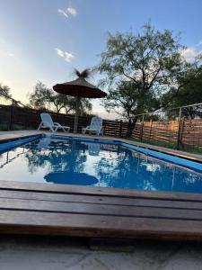 una piscina con 2 sillas y una sombrilla en Ikigai en Los Molles