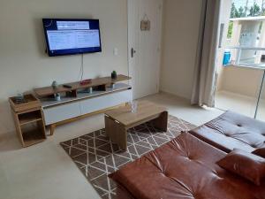 a living room with a couch and a flat screen tv at Apartamento Descubra Palhoça - Pinheira in Palhoça