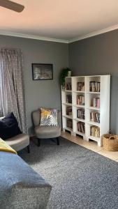 a living room with a chair and book shelves at The Palms 3 bedroom loft apartment in leafy suburb in Durban