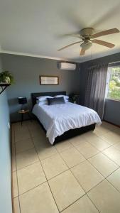 德班的住宿－The Palms 3 bedroom loft apartment in leafy suburb，一间卧室配有一张床和吊扇