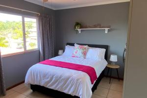 a bedroom with a bed with a pink blanket and a window at The Palms 3 bedroom loft apartment in leafy suburb in Durban