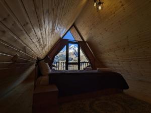 a bedroom with a large window in a wooden room at Cottage Caucasus in Stepantsminda