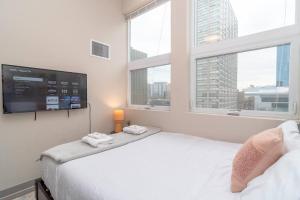 a bedroom with a bed with a tv and windows at McCormick Place 2br-2ba with Optional Parking, Patio, Gym access for 6 guests in Chicago