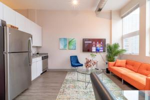 sala de estar con sofá naranja y cocina en McCormick Place 2br-2ba with Optional Parking, Patio, Gym access for 6 guests en Chicago