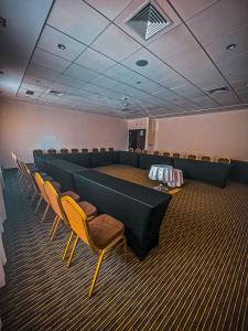 Ecohotel Talca في تالكا: قاعة اجتماعات مع كراسي وطاولة وطاولات طويلة