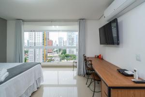 um quarto com uma cama, uma secretária e uma janela em THE EXPRESSION BUENO em Goiânia
