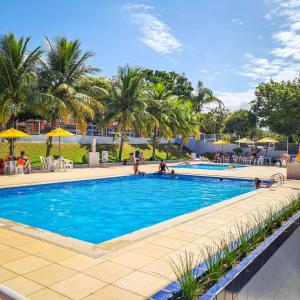 a swimming pool with palm trees and people sitting around it at Estada inesquecível 11 Guarapari/Peracanga-Bacutia in Guarapari