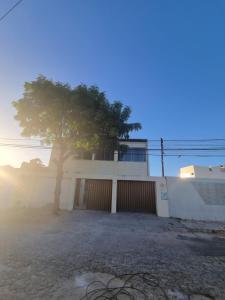 uma árvore em frente a um edifício branco com uma garagem em Loft's Rio em Aracaju