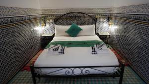 a small bedroom with a bed with white sheets at Riad Green House in Fès