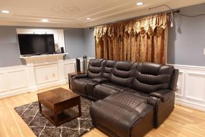 a living room with a leather couch and a television at Handsome Home - 4 minutes close to Metro in Lanham