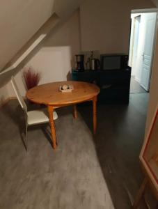 una mesa de madera y una silla en la sala de estar. en Chambre en campagne proche de la mer 1, en Tréméreuc
