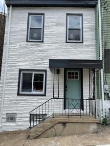 a white house with a green door and stairs at Hip and Bright Lawerenceville 2 Bed Easy Parking in Pittsburgh
