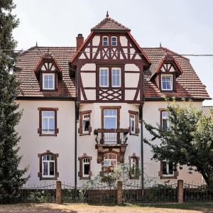 uma casa grande com uma cerca em frente em Charmante, großzügige Ferienwohnung Villa Fleurie em Bretten