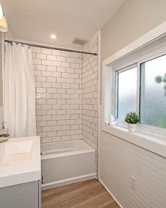 a white bathroom with a tub and a sink and a window at Hip and Bright Lawerenceville 2 Bed Easy Parking in Pittsburgh