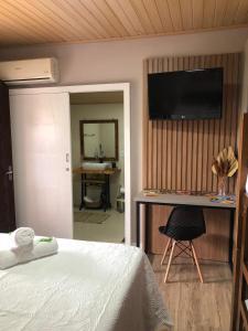 Un dormitorio con una cama y un televisor en una pared. en Suites da Lu, en Penha