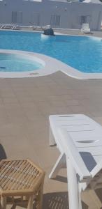 un tavolo bianco e una panca accanto alla piscina di Desconecta en la isla mítica ad Arrecife