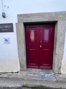 una puerta roja en el lateral de un edificio en Slowly-Com Vagar en Mourão