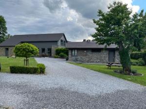 a house with a tree and a gravel driveway at Les midis au vert - gîte pour 11 personnes in Stavelot