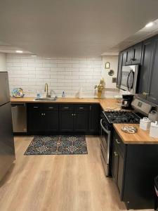 cocina con armarios negros y suelo de madera en Modern & Chic XL Studio w EZ City Airport Access, en Pittsburgh