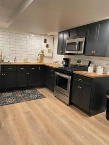 a kitchen with black cabinets and stainless steel appliances at Modern & Chic XL Studio w EZ City Airport Access in Pittsburgh