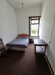 a room with a bed and a table and a window at HOSTAL PLAYA ANCHA in Valparaíso