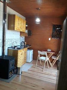 a kitchen with a stove and a table with a chair at Pousada Chales Aconchego Serrano in Bom Jardim da Serra