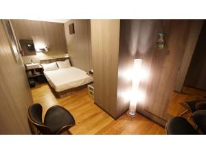 um pequeno quarto com uma cama e uma luz na parede em hotel mio omiya - Vacation STAY 64001v em Saitama