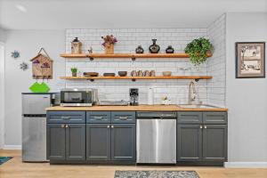 una cocina con armarios grises y electrodomésticos de acero inoxidable en Trendy & Hip South Side Studio Walk to Downtown, en Pittsburgh
