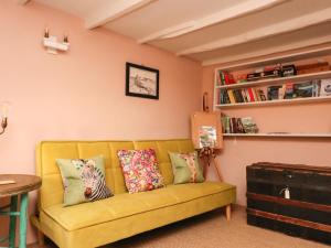 a living room with a yellow couch with pillows at 4 Cumberland Cottages in Kingsbridge