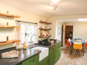 een keuken met groene kasten en een wastafel bij 4 Cumberland Cottages in Kingsbridge